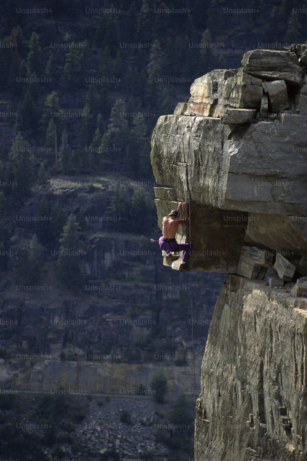 a man hanging from a rope on top of a cliff