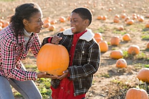 a woman holding a pumpkin next to a young girl