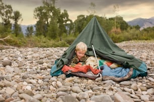 Young boy playing in collapsed tent outdoors