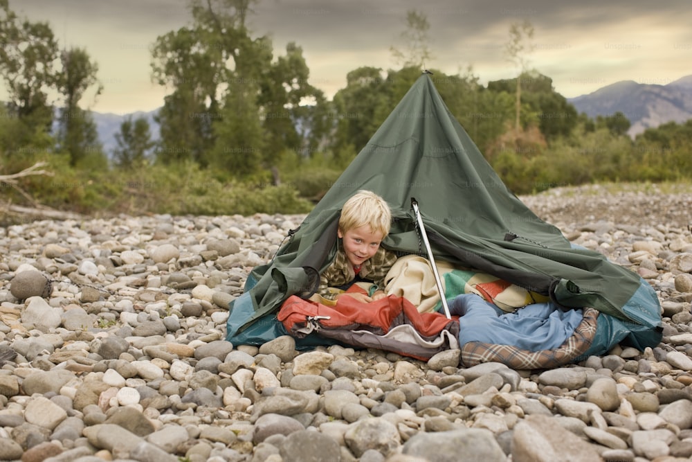Young boy playing in collapsed tent outdoors