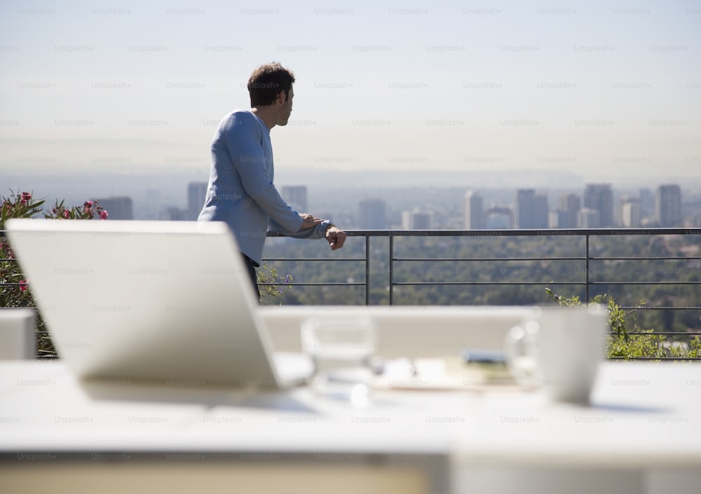Ein Mann, der auf einem Balkon mit Blick auf eine Stadt steht