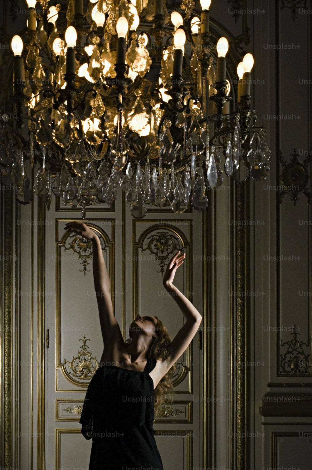 a woman standing in front of a chandelier