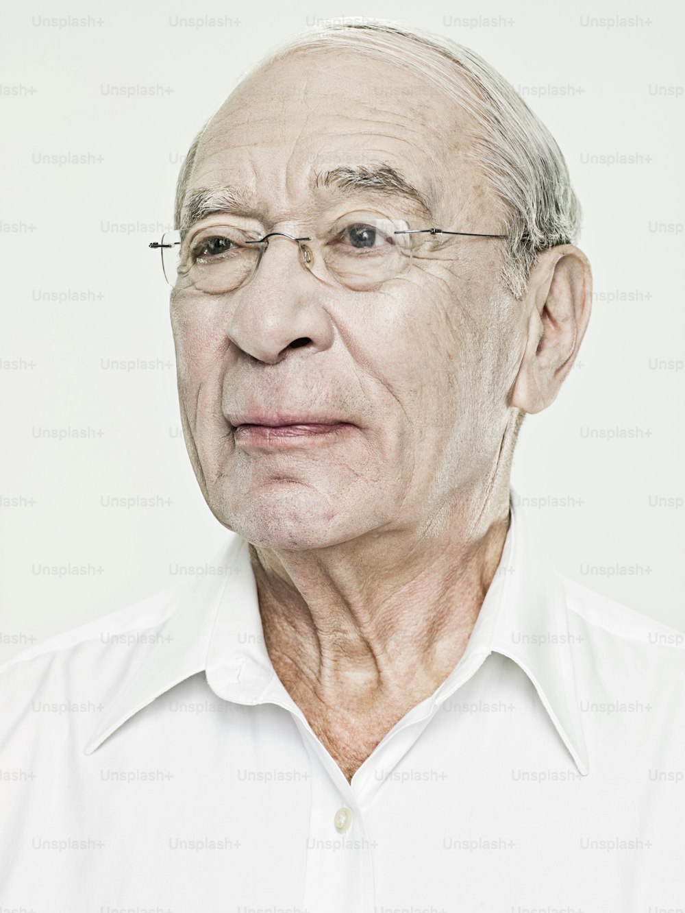 un homme âgé avec des lunettes et une chemise blanche