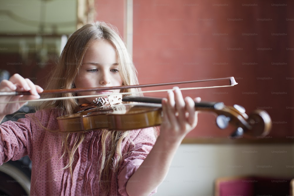 uma menina tocando um violino em um quarto