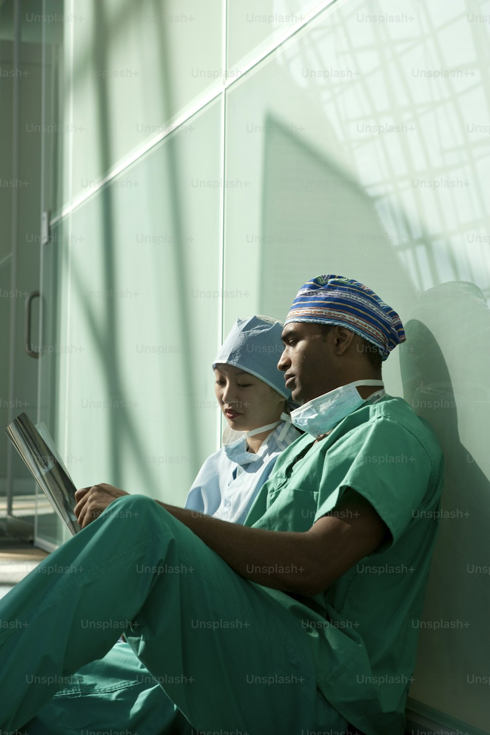 a man in scrubs sitting next to a woman on a laptop