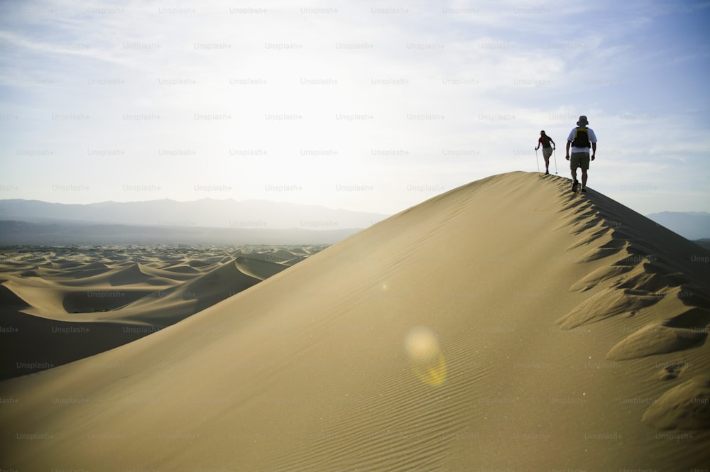 Dos personas de pie en la cima de una duna de arena