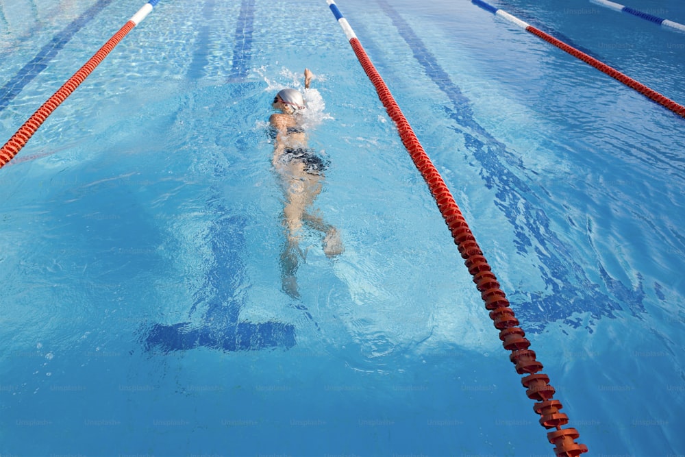 빨간색과 흰색 선이 있는 수영장에서 수영하는 사람