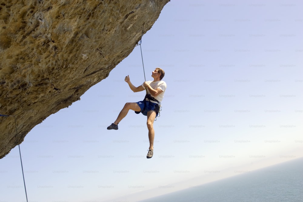 a man hanging from a rope on top of a cliff
