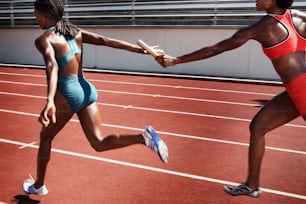 two women running on a track holding hands