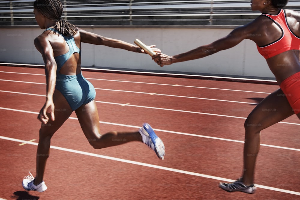 two women running on a track holding hands