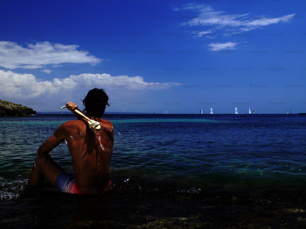 a man sitting in the water with a baseball bat in his hand