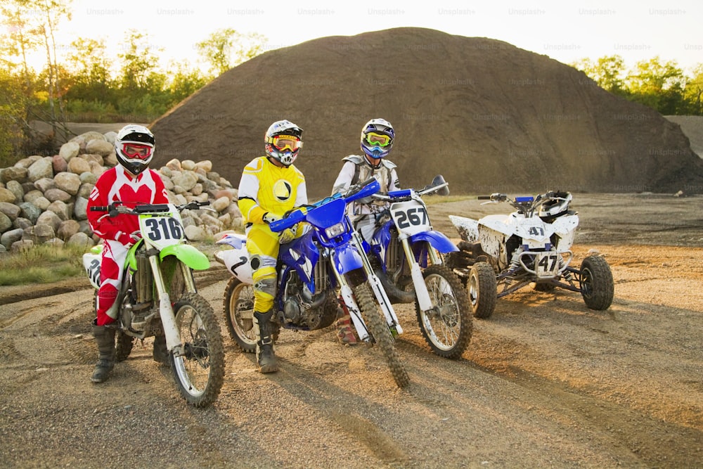 a group of three dirt bikes sitting on top of a dirt field