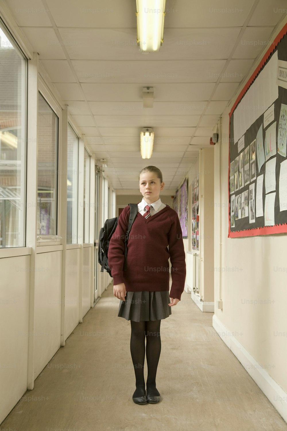 a girl in a school uniform standing in a hallway