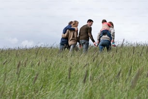 a group of people walking across a grass covered field