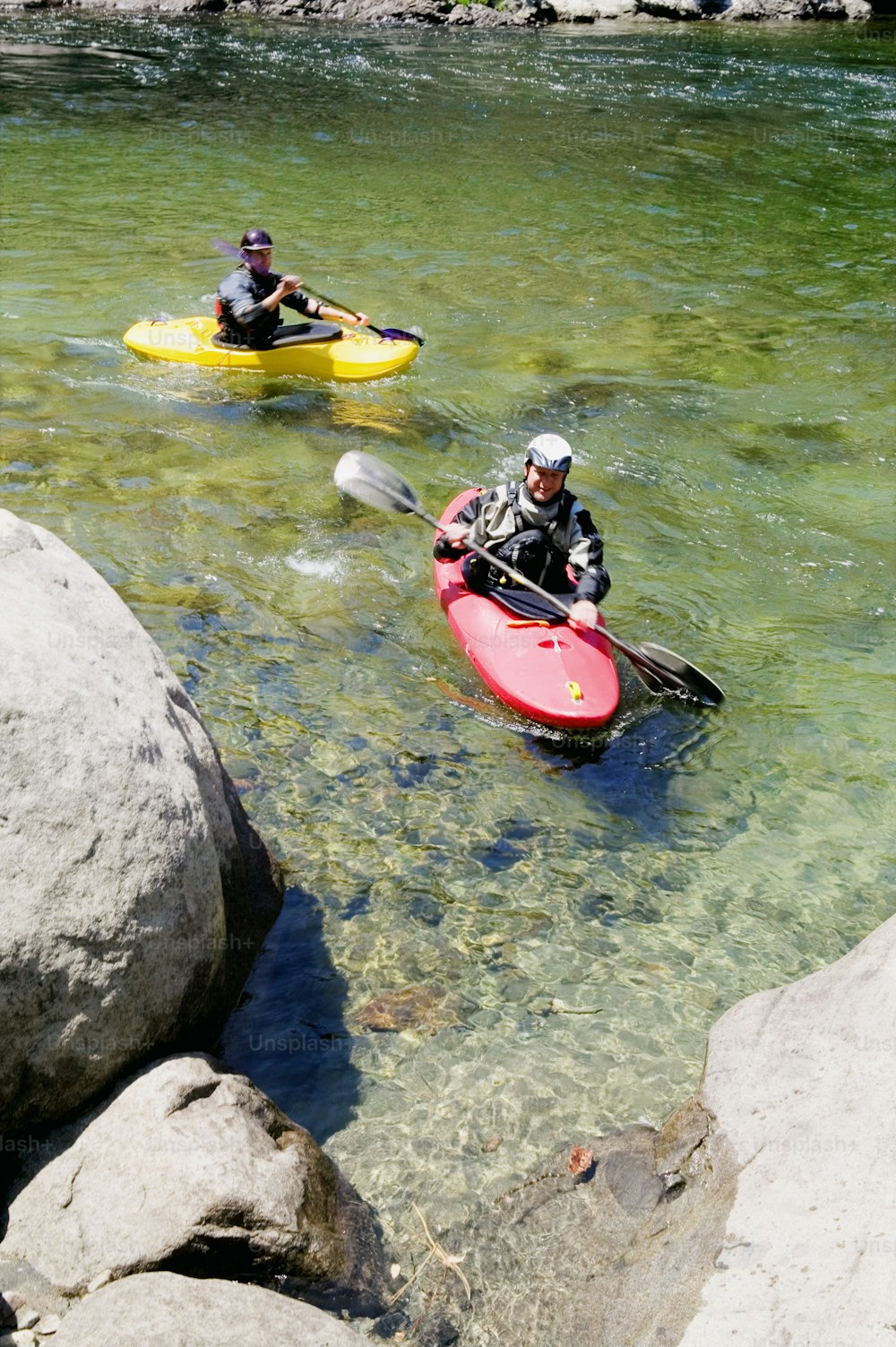 two people in kayaks paddling through a river