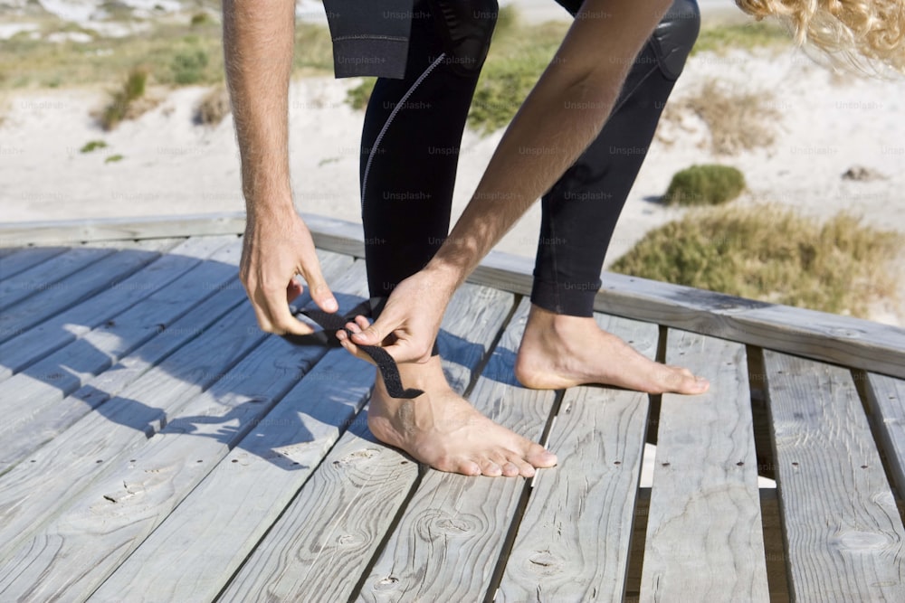a man tying a pair of barefoot shoes on a boardwalk