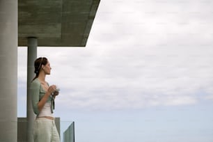 a woman standing on a balcony next to the ocean