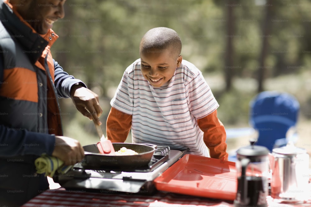 a couple of people standing around a table with food