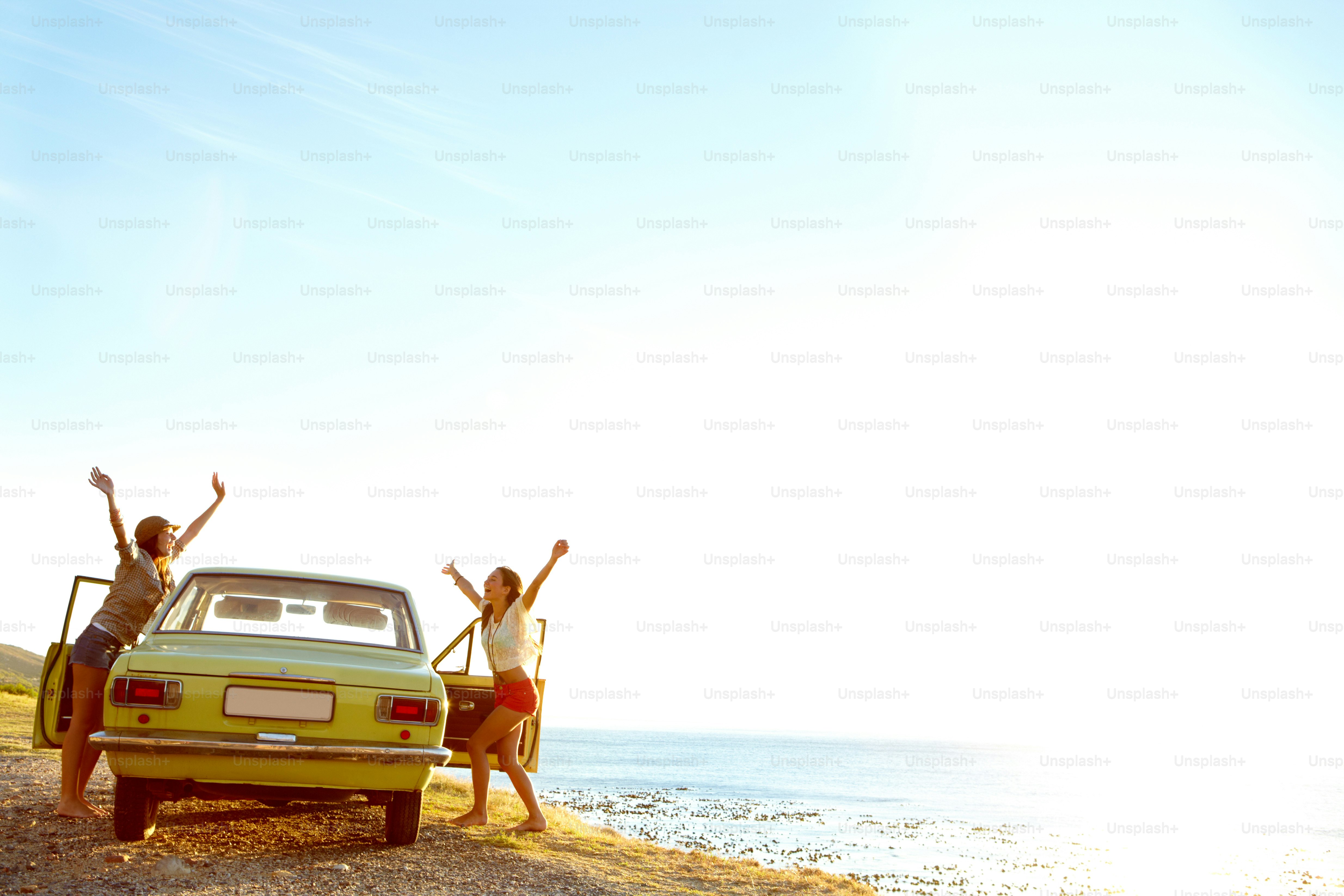 Duas mulheres jovens fora de seu carro na praia depois de uma roadtrip