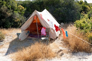 a tent set up in a field with clothes hanging out to dry