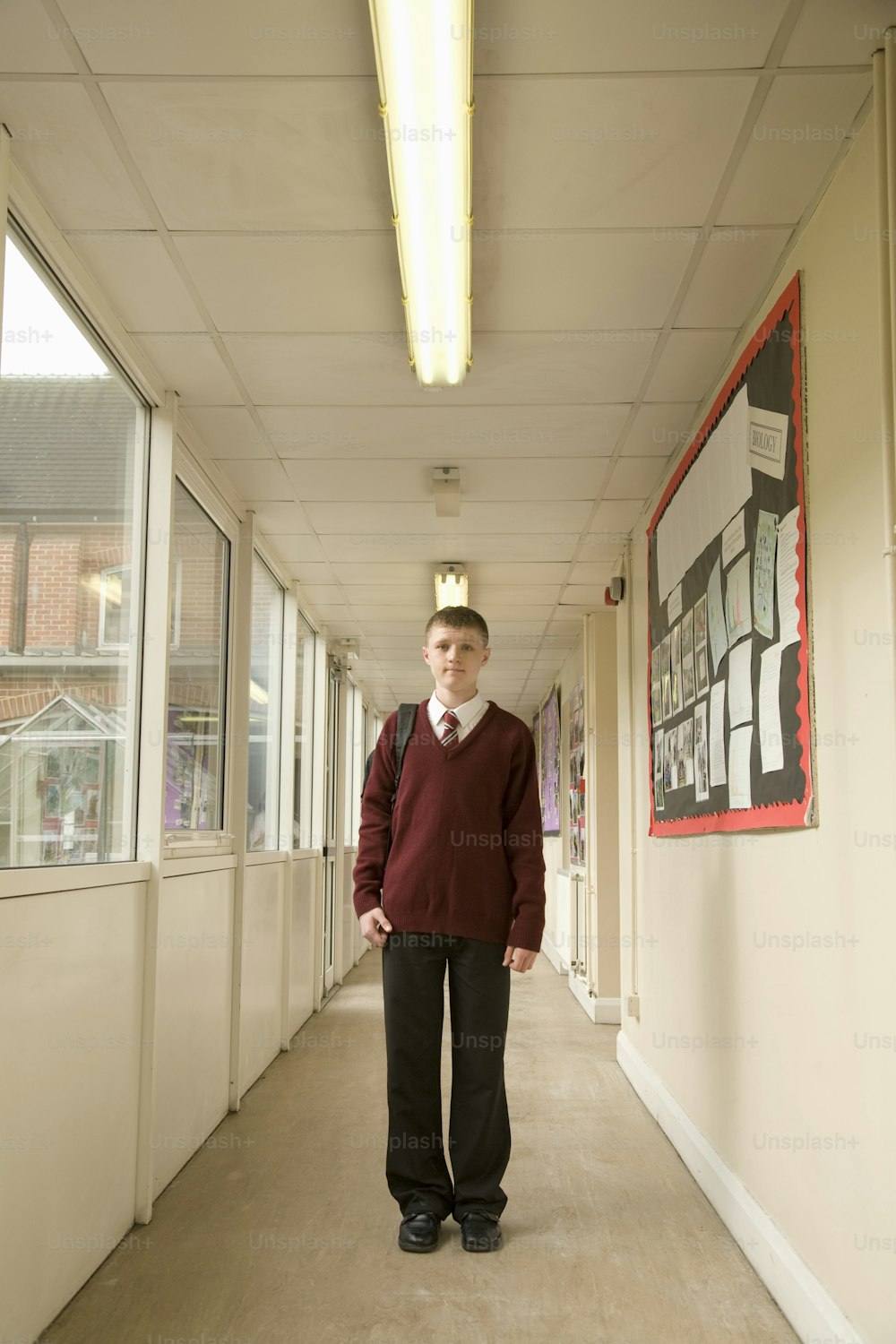 a man standing in a hallway with his hands in his pockets