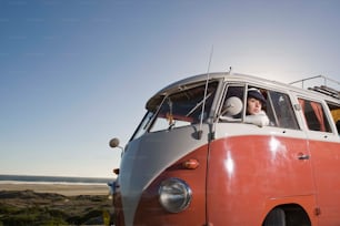 a man sitting in the front of an orange and white van