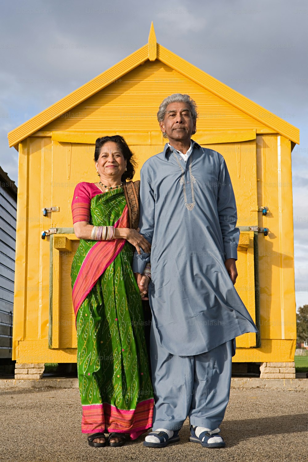 a man and a woman standing in front of a yellow building