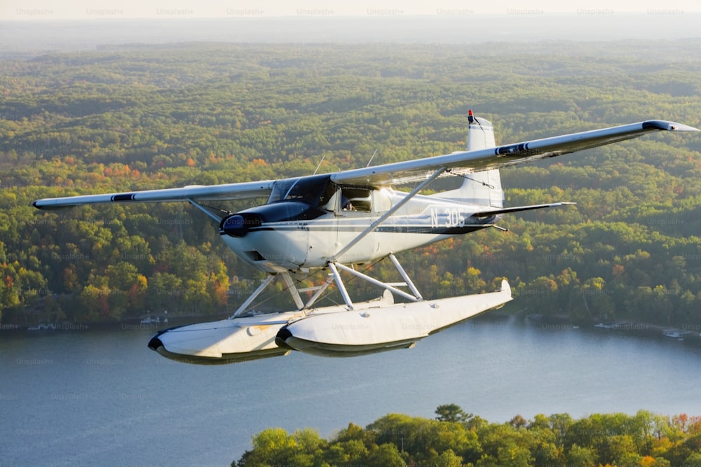 a small plane flying over a lake surrounded by trees