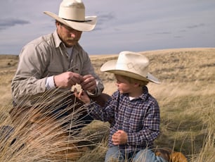 Cowboy e filho pequeno estudando a natureza na propriedade do rancho em Big Timber, Montana
