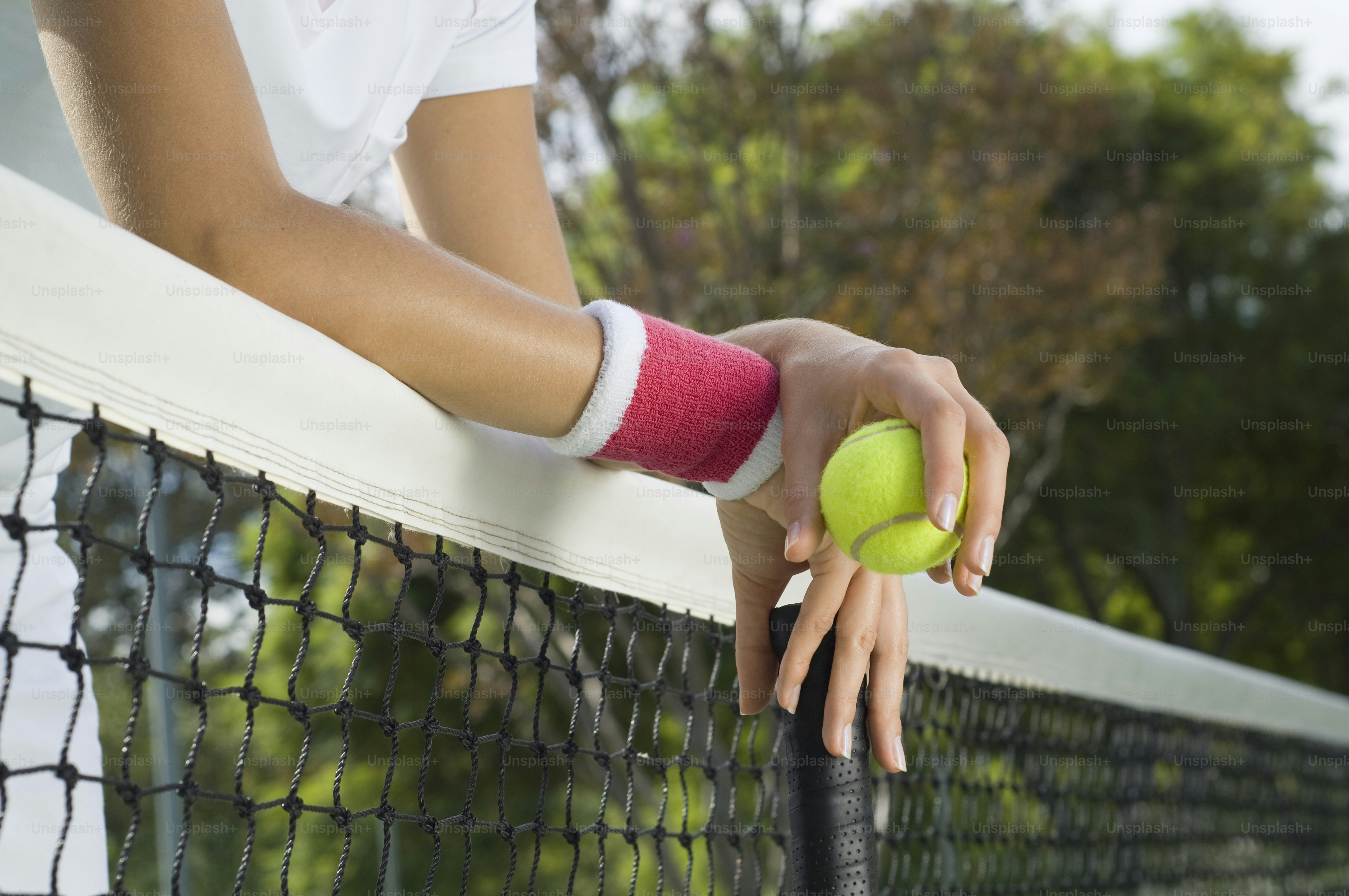 Eine Frau, die einen Tennisball und einen Schläger auf einem Tennisplatz hält