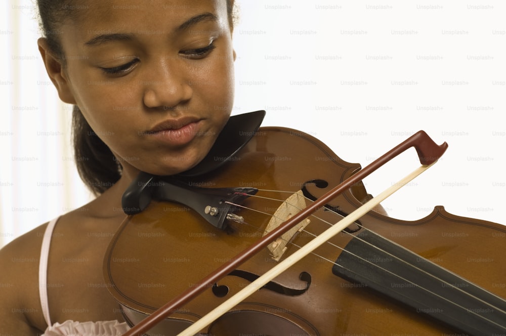 a young girl playing a violin with a bow