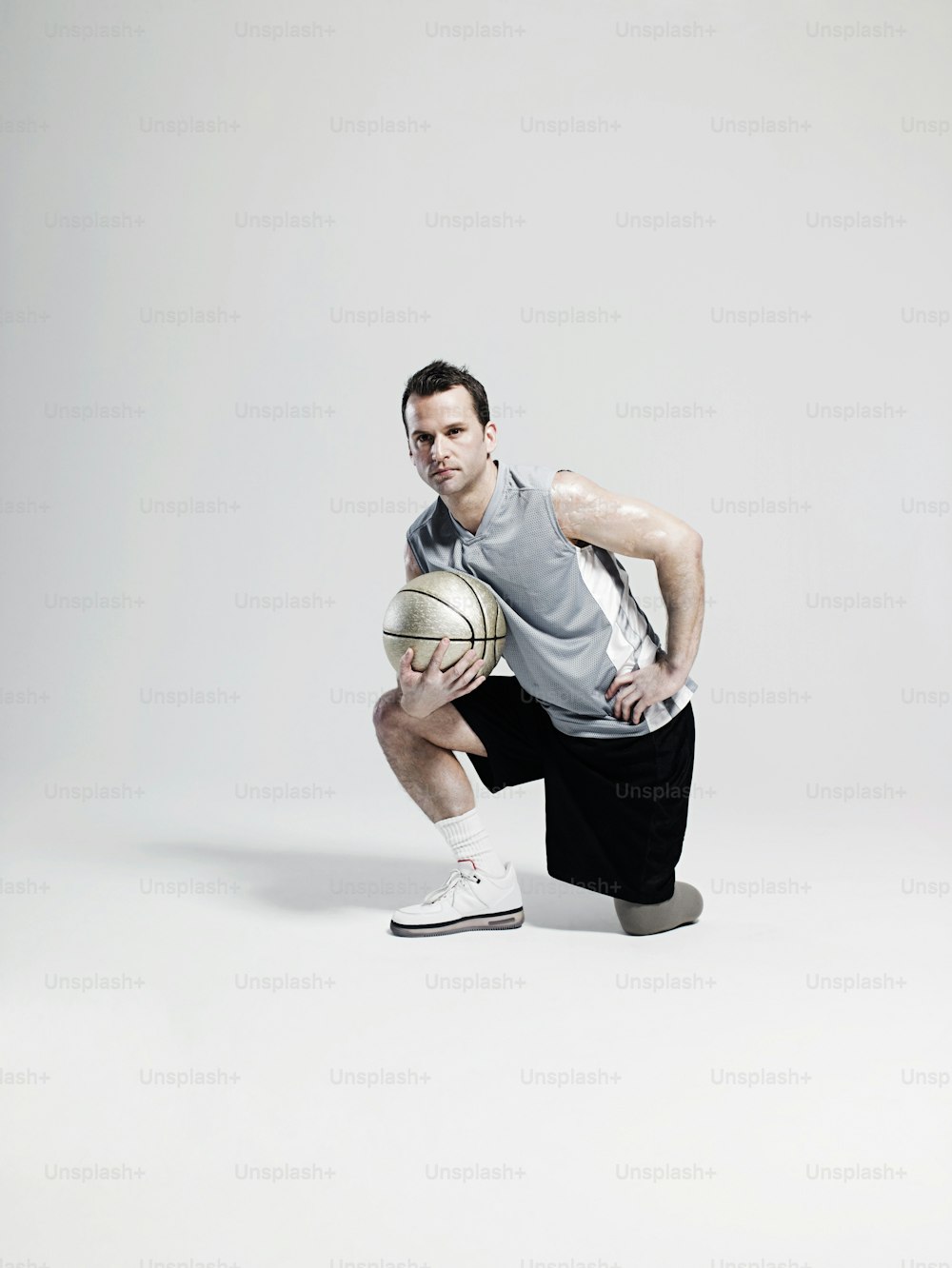 Un hombre arrodillado sosteniendo una pelota de baloncesto