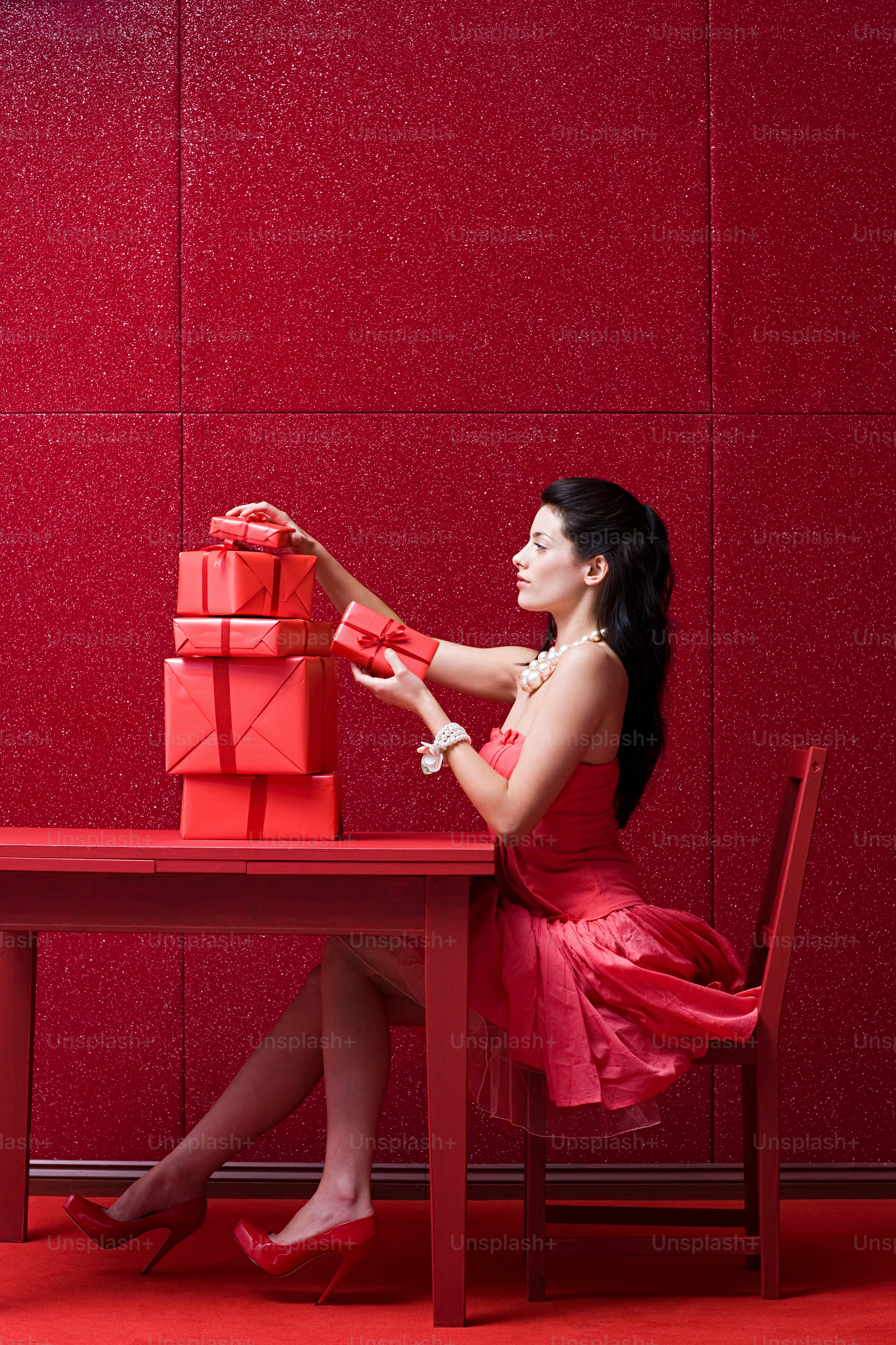 A woman in a red dress sitting at a red table photo – Woman Image on ...