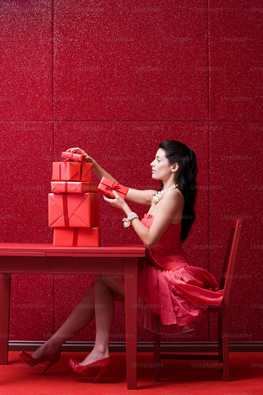 a woman in a red dress sitting at a red table