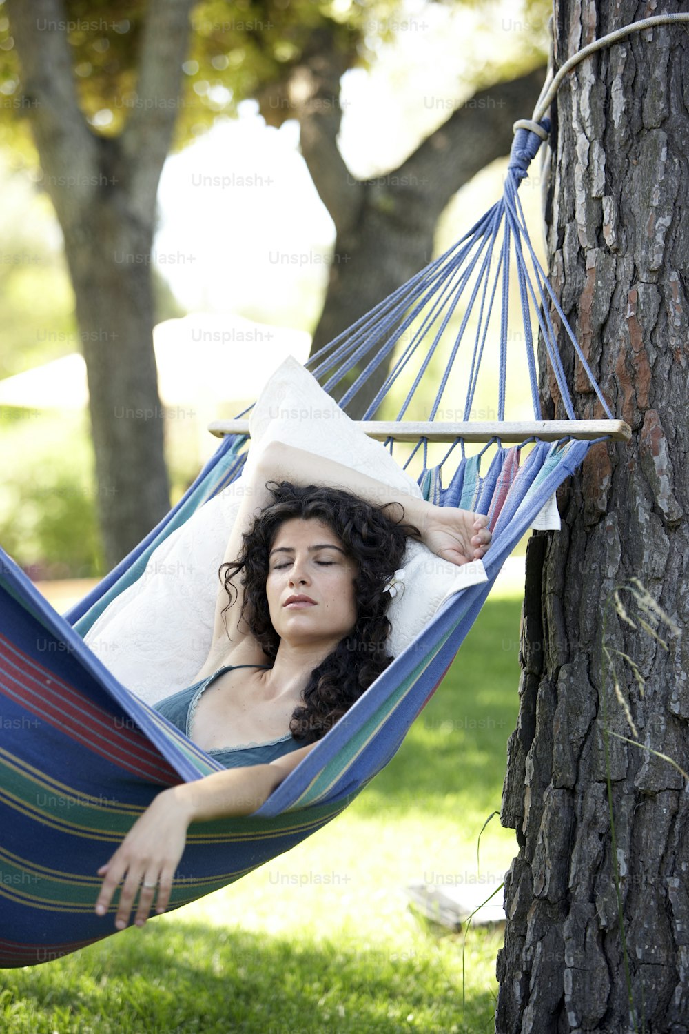a woman laying in a hammock in a park
