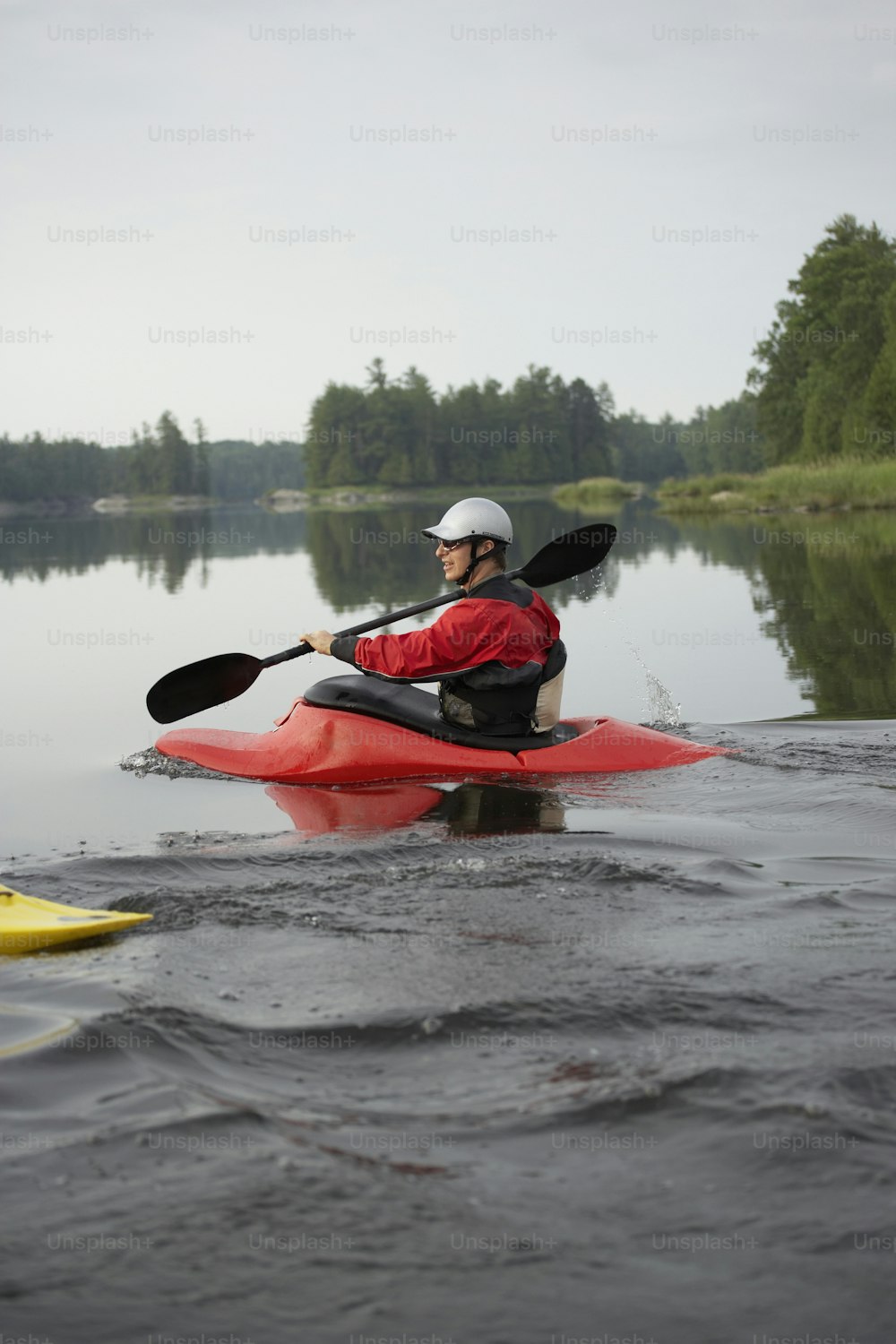 Un uomo in un kayak rosso che pagaia sull'acqua