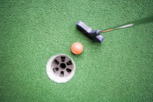 una pelota de golf y un putter en una alfombra verde