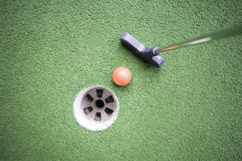 a golf ball and putter on a green carpet