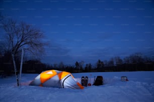 an orange and white tent sitting in the snow
