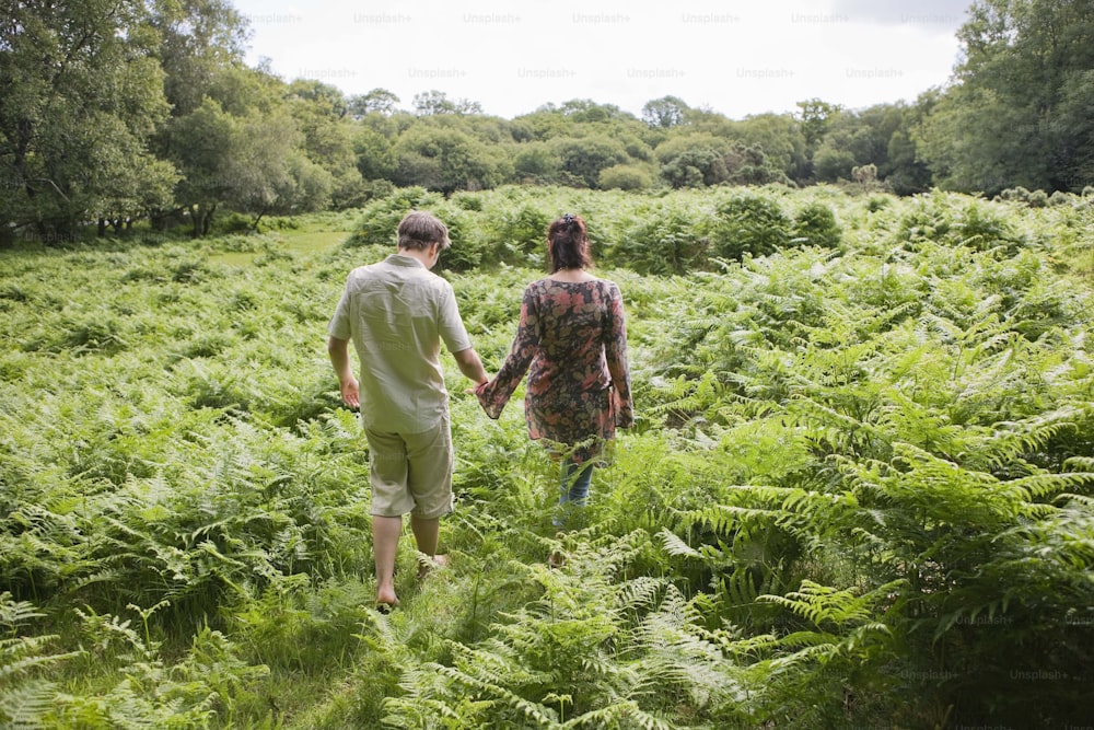 a man and woman walking through a lush green field