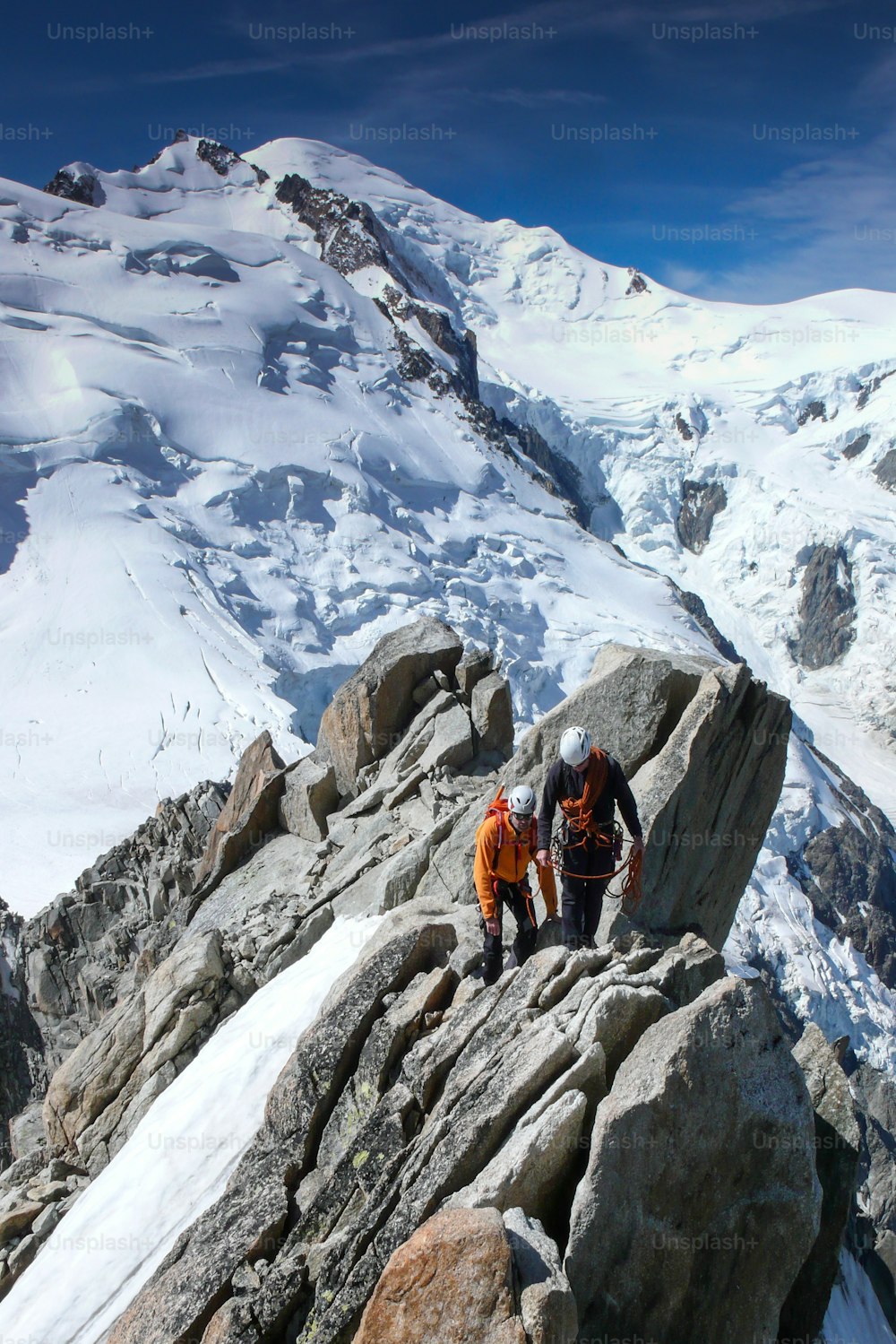 guide de montagne et un client masculin sur une crête rocheuse se dirigeant vers un haut sommet des Alpes françaises près de Chamonix par une belle journée d’ét�é
