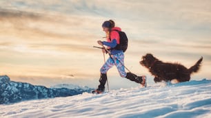 Fille sportive avec son chien lors d’une randonnée alpine sur la neige