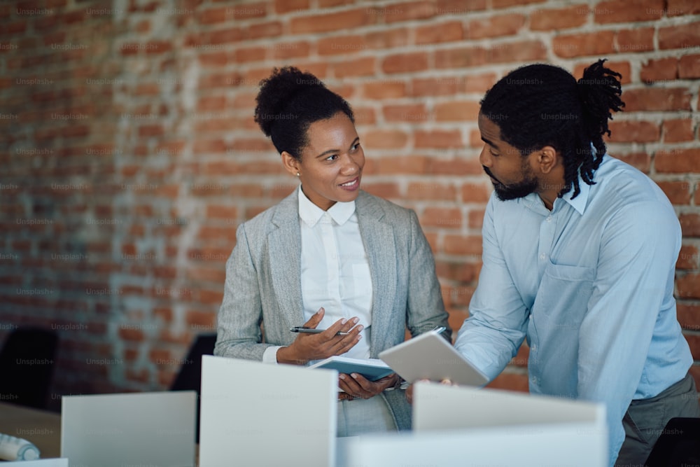 Empresarios negros hablando entre sí mientras trabajan en una oficina corporativa. La atención se centra en la mujer de negocios.
