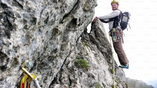 Bergführer-Kletterer am Rande einer steilen Kletterroute auf dem Weg in die nächste Seillänge auf einer Hartkletterroute in der Schweiz