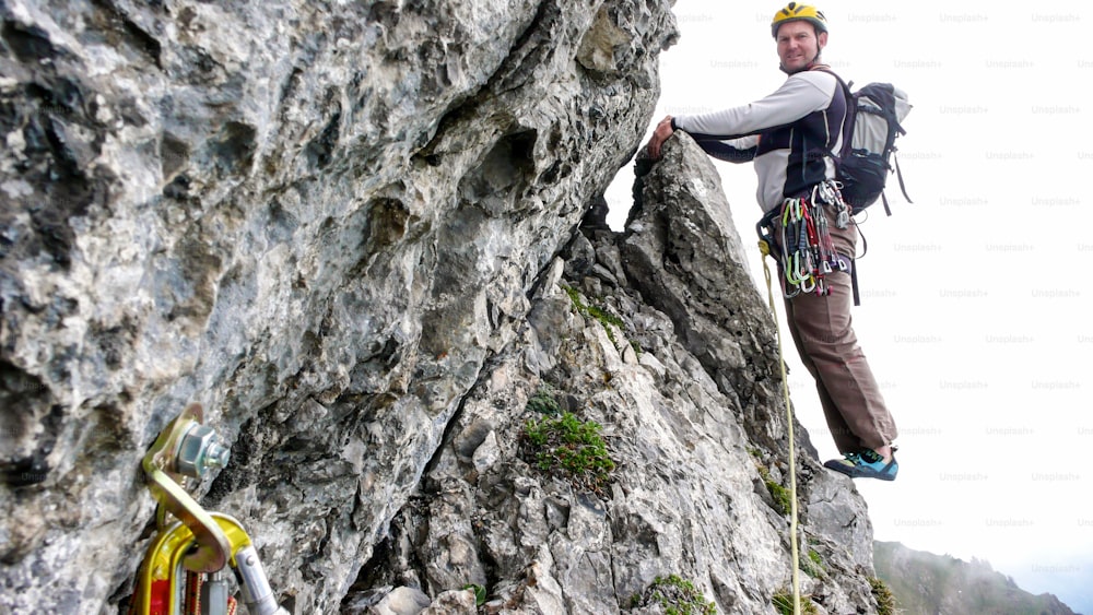 Guía de montaña escalador en roca al borde de una ruta de escalada empinada que se dirige al siguiente largo en una ruta de escalada en roca dura en Suiza