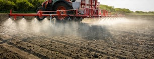 Tractor rociando pesticidas en el campo con rociador