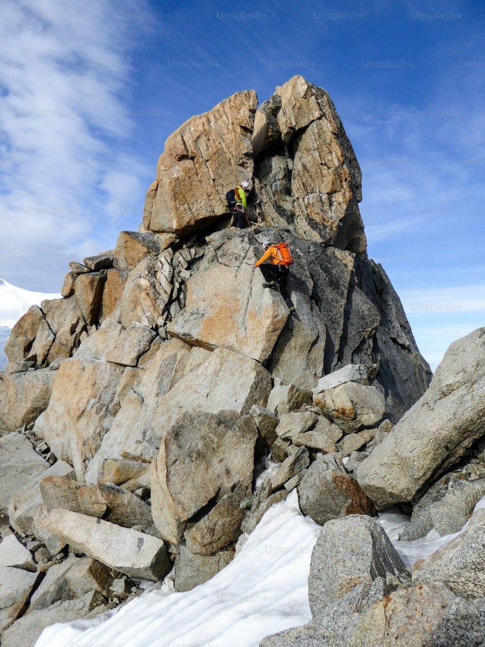 Bergführer und ein männlicher Kunde auf einem Felsgrat auf dem Weg zu einem hohen Gipfel in den französischen Alpen bei Chamonix an einem schönen Sommertag