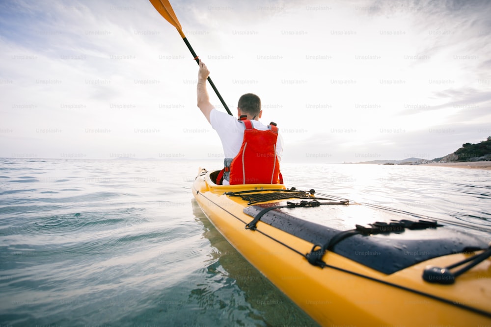 Rear view of man kayaker paddling at sea.