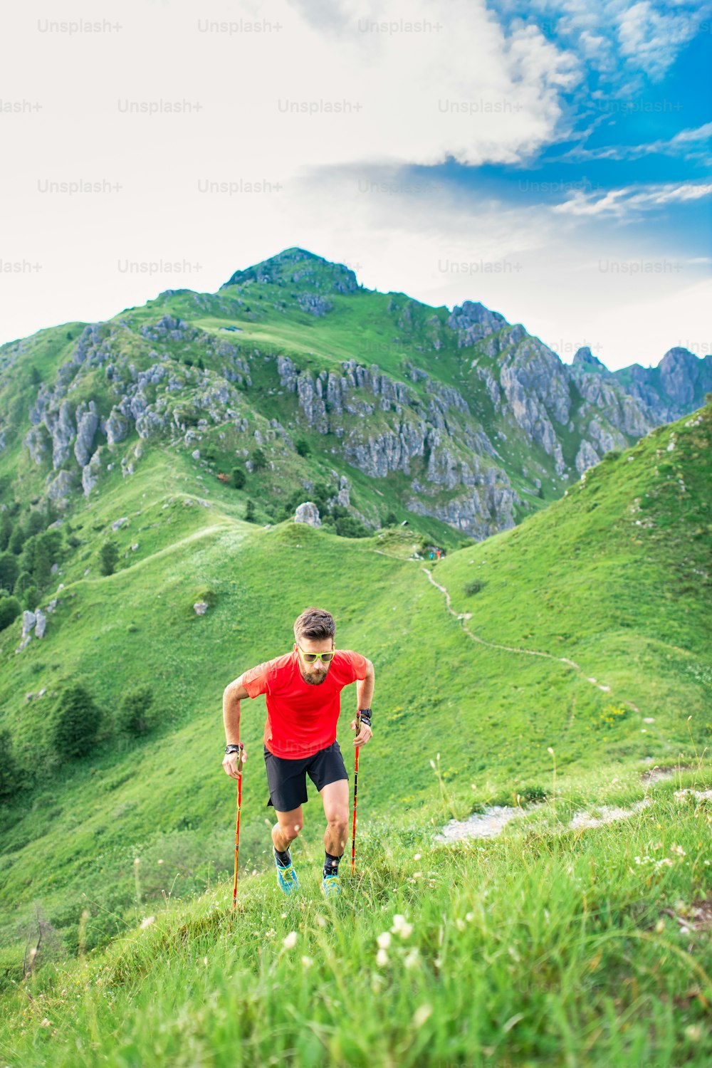 Man climbs steep mountain path with use of sticks