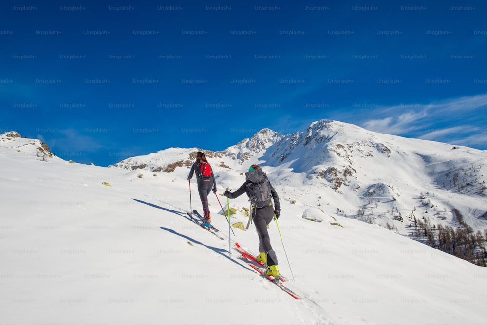 A couple of women practice ski mountaineering.